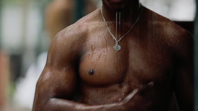 Sexy macho man with muscular body take a shower under summer rain