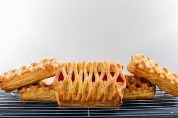 Puff pastries with strawberry and cheese filling on baking rack