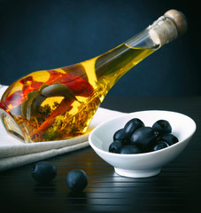 Bottle of olive oil with olives on a wooden background