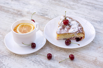 Вкусный кусок вишневого пирога на белой тарелке и белая чашка горячего чая с лимоном. Крупный план. Мокап. - obrazy, fototapety, plakaty