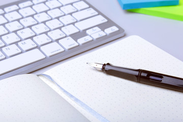 Business accessories on desktop: notebook, diary, fountain pen, glasses. Macro with blur and soft focus.