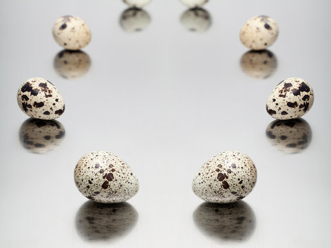 Quail eggs on a mirror metallic background.