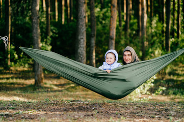 Modern Masculinity. Man in non-stereotypical role. Father caring his lovely daughter outdoor in summer.  Happy family expressing funny kind emotions at nature.  Parent with child leisure in hammock.