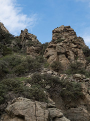Outcropping of Ancient Metamorphic Rock in Montana from Below with blue sky and scattered white cloudls above.