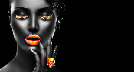 Model, goldene Lippen, Wimpern und Schmuck - goldener Ring zur Hand. Isoliert auf schwarzem Hintergrund. Schönheitsfrauengesicht, schönes Make-up. Wunderschönes Damenmode-Kunstporträt. © Subbotina Anna