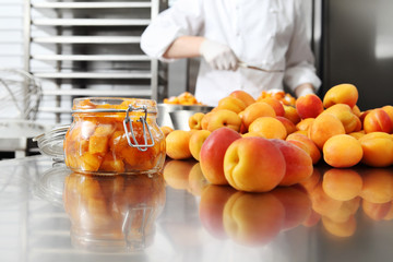 Jam from apricots in a glass jar on a polished stainless steel surface in pastry worktop