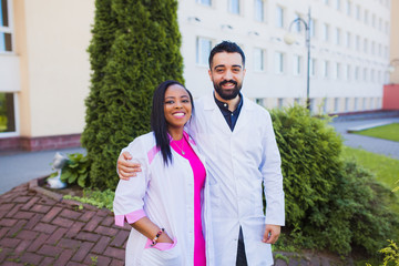 multiracial team two young doctors near the hospital. African interns are happy after the exams....