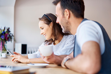 Couple using smartphone and drinking coffee in cafe