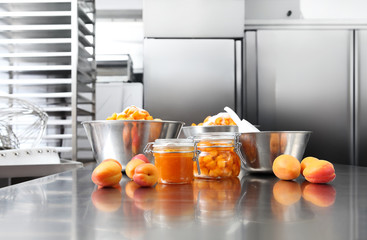 Jam from apricots in a glass jar on a polished stainless steel surface in pastry worktop