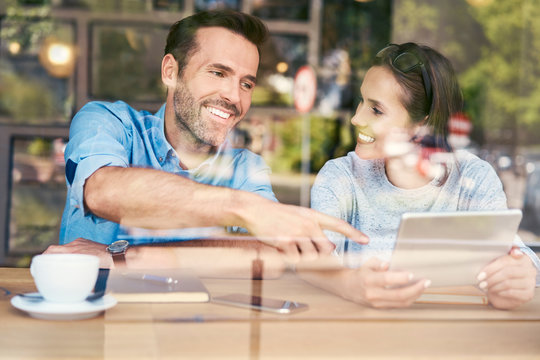 Happy couple having coffee in a cafe and and using digital tablet