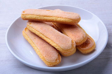 Ladyfinger biscuit savoiardi in plate. ingredient for homemade tiramisu cake in close up.