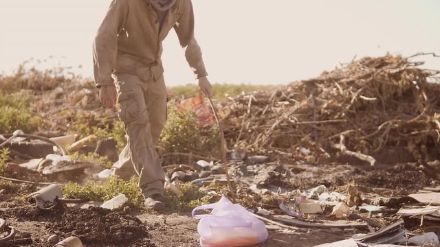 portrait of a homeless man in a dump with walking goes looking for food slow motion video. homeless roofless person looking for lifestyle food in a dump. refugee homeless illegal immigration poverty