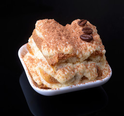 Piece of appetizing homemade tiramisu cake on plate in close up.