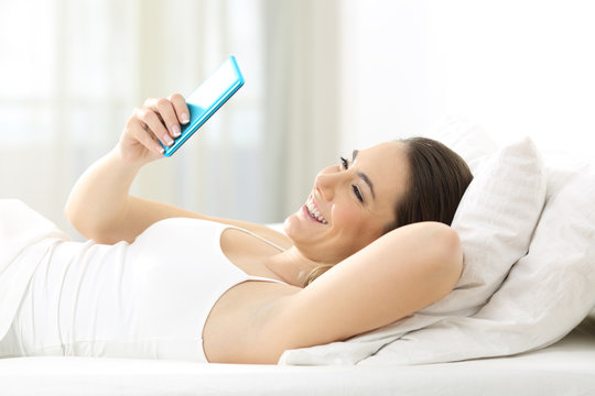 Woman reading text in a phone on the bed