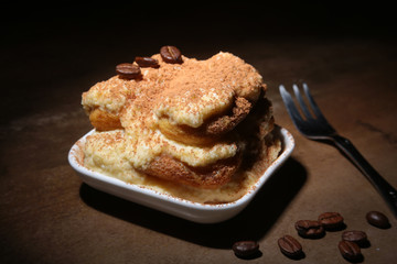 Piece of appetizing homemade tiramisu cake on plate in close up.