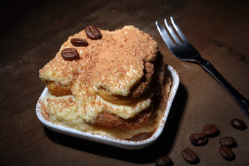 Piece of appetizing homemade tiramisu cake on plate in close up.