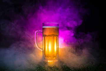Creative concept. Single beer glass on green grass at dark toned foggy background. Watch football (soccer) with beer concept.