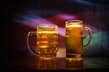 Creative concept. Beer glasses on table at dark toned foggy background with blurred view of flag of Germany.