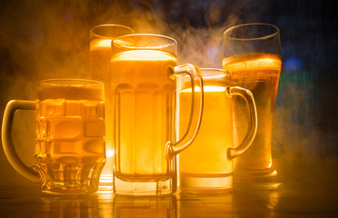 Creative concept. Beer glasses on table at dark toned foggy background with blurred view of playing game at the stadium.