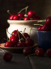 still life picture in the dark of fresh cherry on plate on wooden black background. fresh ripe cherries. soft focus image 