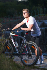 Obraz premium Healthy Lifestyle and Sport Concepts.Caucasian Male Athlete with Mountain Bike Posing Against Waterfall Outdoors.