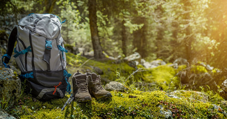 Backpack and hiking boots in forest - obrazy, fototapety, plakaty