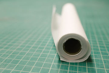 Roll of exam table paper on a green cutting mat 
