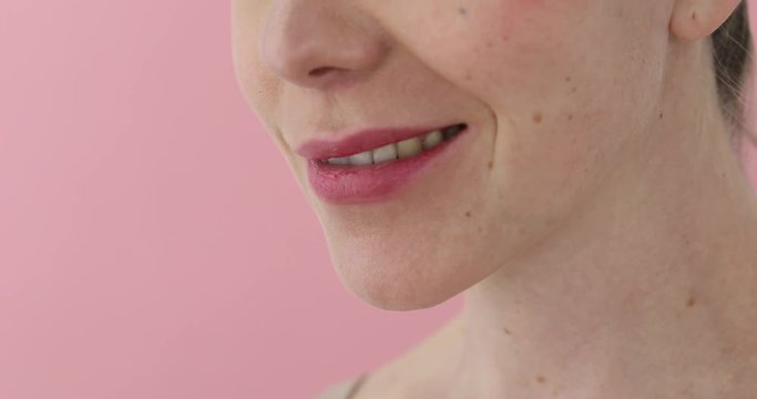 Close-up of a woman sends an air kiss with her hand and lips on a pink background