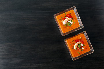 Soup gazpacho with shrimps. Italian Cuisine. Two transparent bowls with soup on a black background. Top View. Copy space.