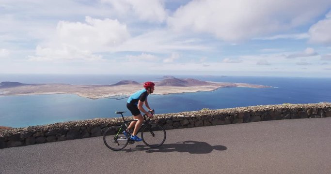 Road bike cyclist sports athlete biking cycling outdoors by ocean. Professional cyclist riding bike on an open road. Active healthy man sport lifestyle. Shot on RED EPIC in SLOW MOTION.