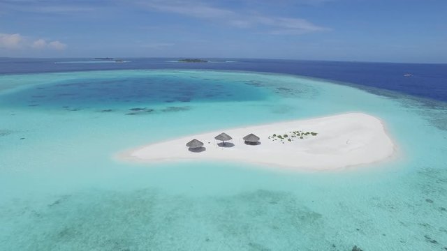 flight over a small tropical sandy island - umbrellas on the sandbank