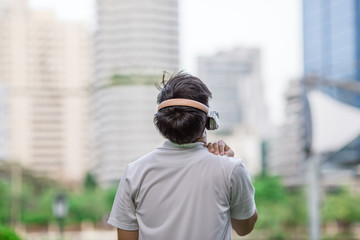 Young man wearing headphones listening to music in the park. Prepare to exercise or relax after exercising.