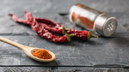 A wooden spoon with chili pepper on a table.