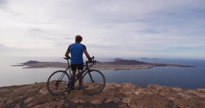 Man cyclist biking on road race cycling on racing bike. Professional cyclist athlete cycling riding bicycle resting looking at view on Lanzarote, Canary Islands, Spain, Europe.