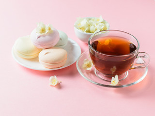 Freshly prepared tea and colored marshmallows and jasmine on a pink table. The composition of the morning Breakfast.