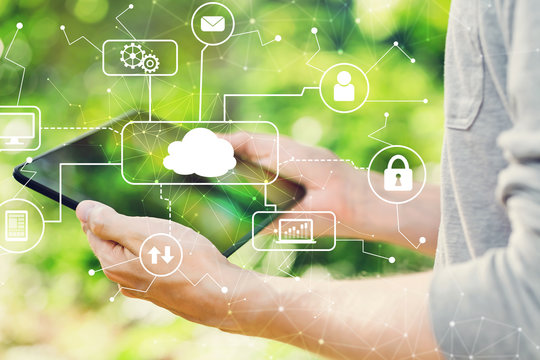 Cloud computing concept with man holding his tablet computer outside in the park