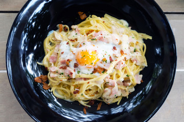 Close up of Spaghetti Carbonara with egg in white plate on the wooden table..