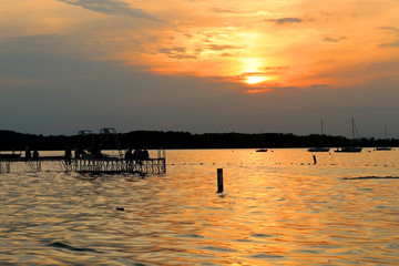 Fototapeta premium Sunset over the lake Mendota. Memorial Union shore with yachts and people silhouettes on a pier enjoying sunset in the city of Madison, the capital of Wisconsin, Midwest USA.