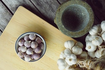 Fresh raw garlic bundle on cutting board, traditional mortar, copy space, kitchen raw ingredient concept