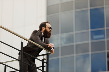 bearded man in sunglasses with a very interesting look with cityscape in the background