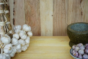 Fresh raw garlic bundle on cutting board, traditional mortar, copy space, kitchen raw ingredient concept