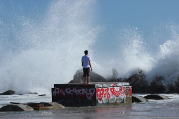 Two young lovers admire huge crashing waves