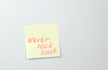 Note on yellow sticker paper sheets with motivation words never look back.