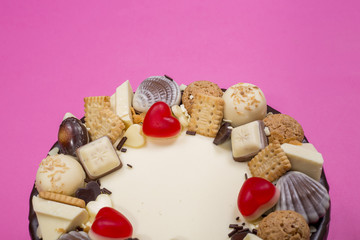 Part of a big festive cake on a pink background, top view.
