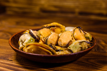 Ceramic plate with prepared mussels on wooden table