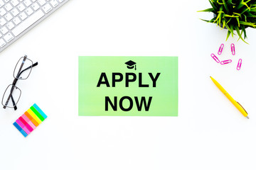 Choose college. Words apply now with graduation cap sign on white student desk with computer top view copy space