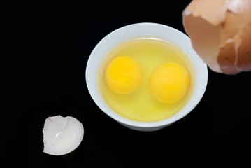Top view of egg yolk in a bowl and egg shell isolated on black background. Copy space