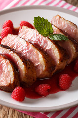 natural food: fried duck breast served with fresh raspberry sauce and mint closeup on a plate. vertical