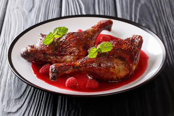 beautiful natural food: fried duck legs served with fresh raspberry sauce and mint closeup on a plate. horizontal