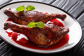 Delicious food gourmet: fried duck legs served with raspberry sauce and mint crispy on a plate. horizontal